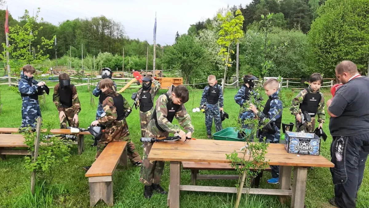 Grupa znajomych podczas gry paintballowej na wieczorze kawalerskim